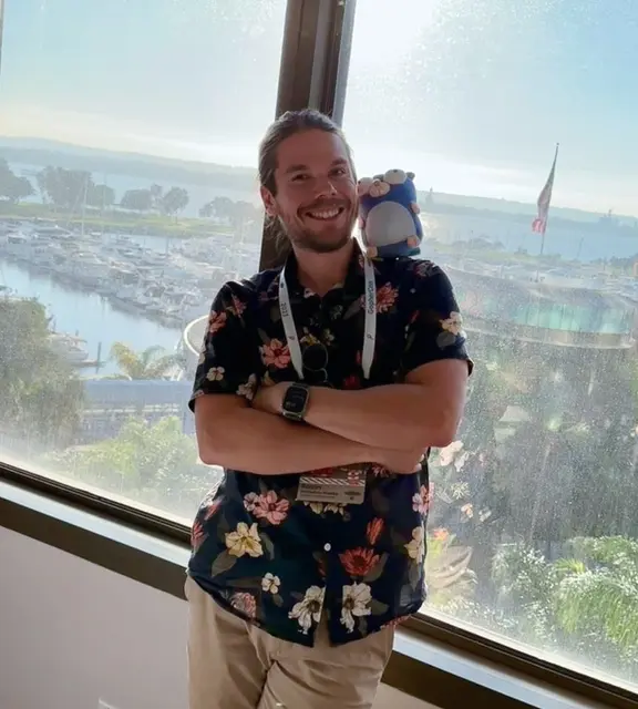Robin Hallabro-Kokko at GopherCon, standing by a window overlooking a marina